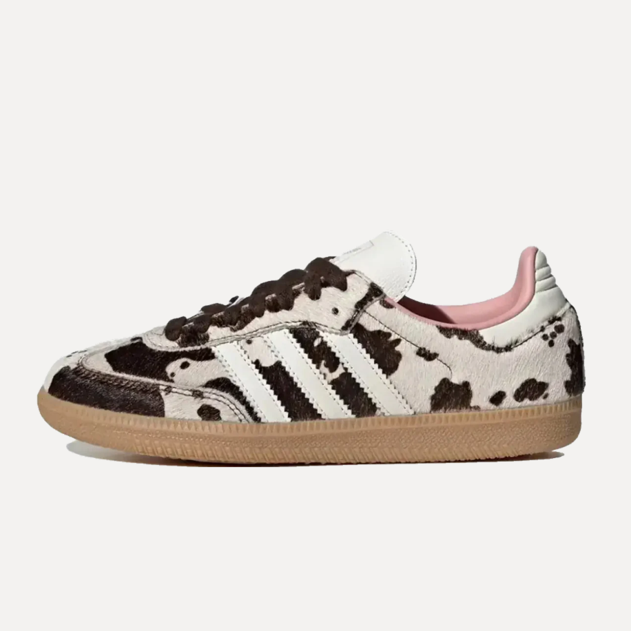 Para sneakersów Adidas Samba w jasnej kolorystyce z charakterystycznym czarno-białym wzorem przypominającym krowią skórę. Buty są pokazane z boku na jasnym, neutralnym tle.