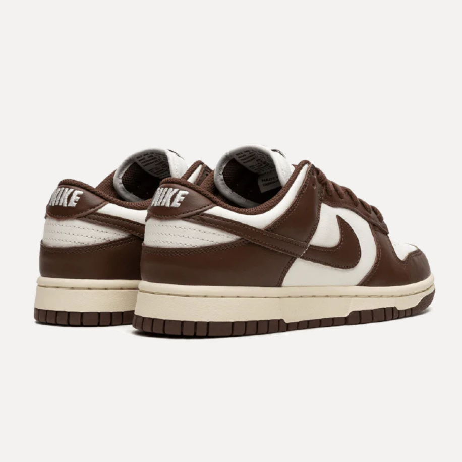 Para sneakersów w połączeniu ciemnego brązu, jasnego beżu i bieli. Buty są ustawione obok siebie na jasnym tle, a ich boczne panele, sznurowadła i podeszwy są wyraźnie widoczne.